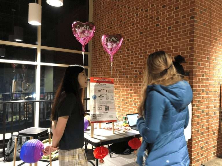 Graduate students standing behind the Wuhan fundraiser board.