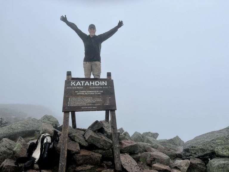 Janelle Lewis posing atop "Katahdin" sign.