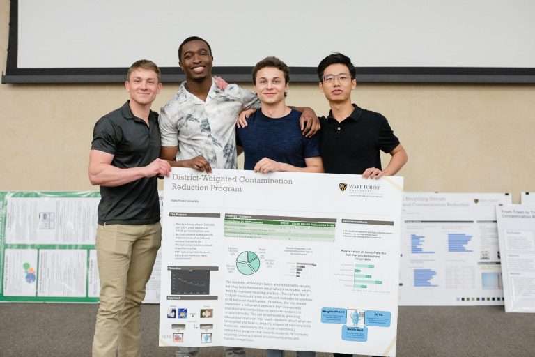Students showcasing their contamination reduction program poster.