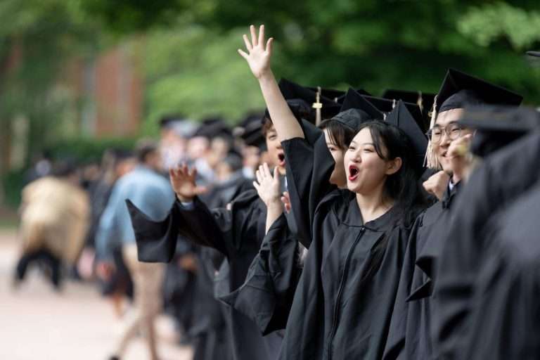 Graduate students cheering in gown.