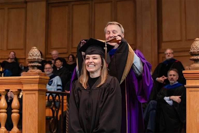 Women getting hood placed onto her head with an excited expression.