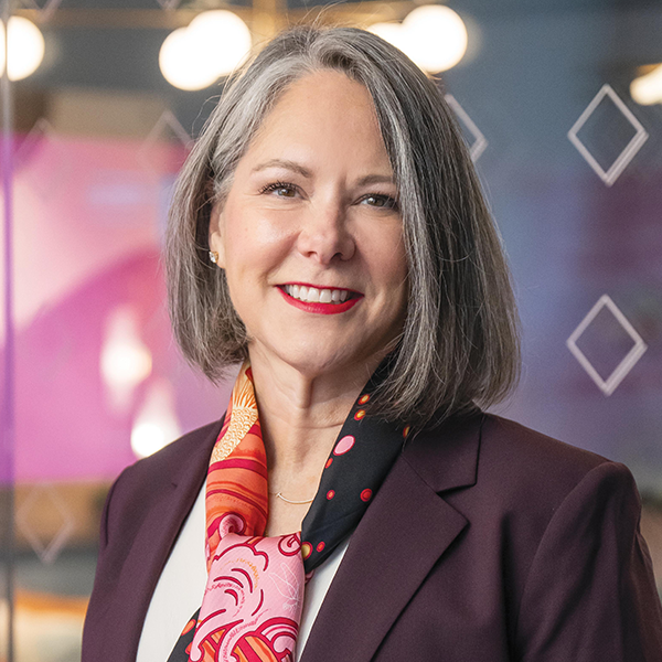 Woman standing in front of glass door, smiling.