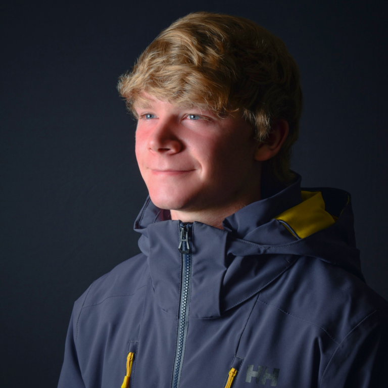 Close-up of a young person wearing a blue hooded jacket with yellow accents, looking to the side.