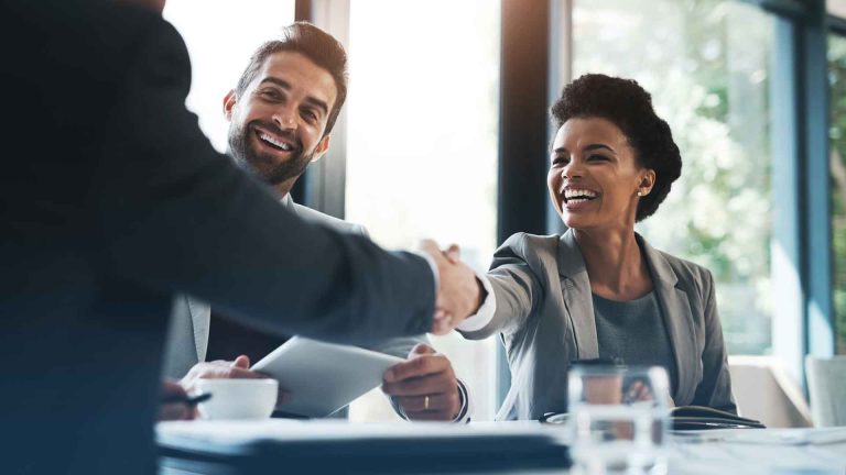 An image of a business meeting as two associates shake hands to greet one another